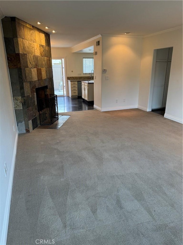 unfurnished living room with sink, ornamental molding, carpet floors, and a tile fireplace