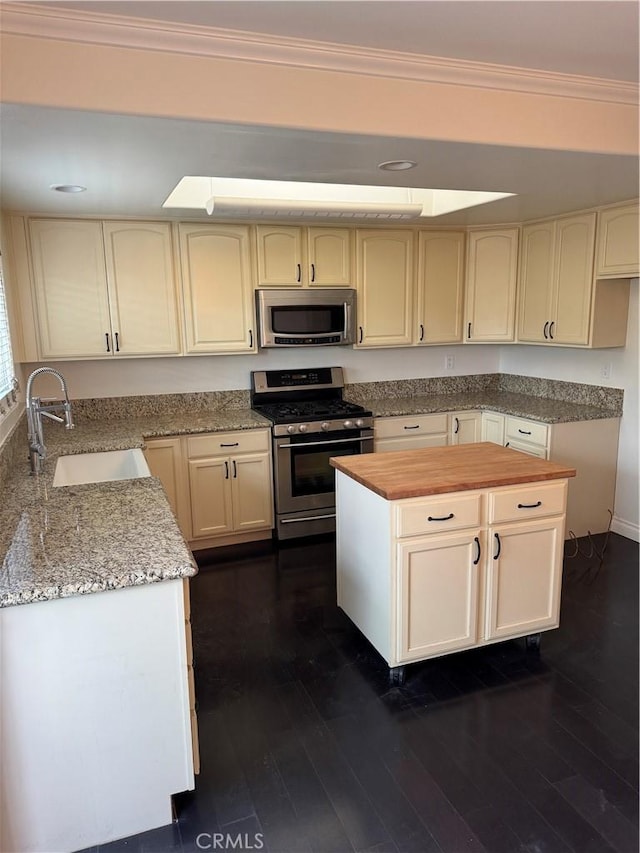 kitchen featuring appliances with stainless steel finishes, crown molding, sink, cream cabinets, and dark hardwood / wood-style floors