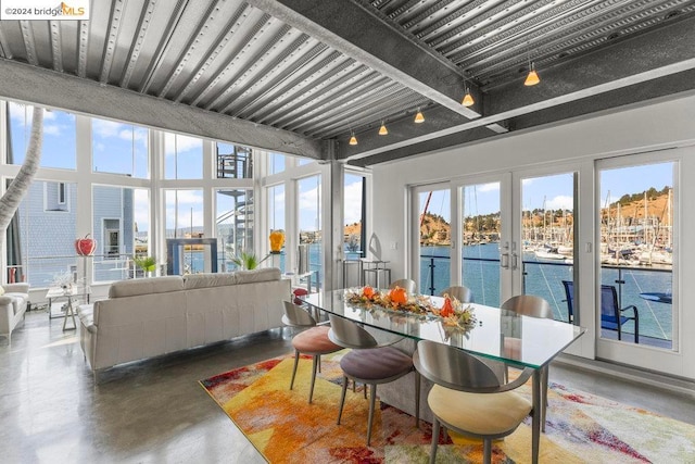 sunroom featuring french doors, a water view, and a healthy amount of sunlight