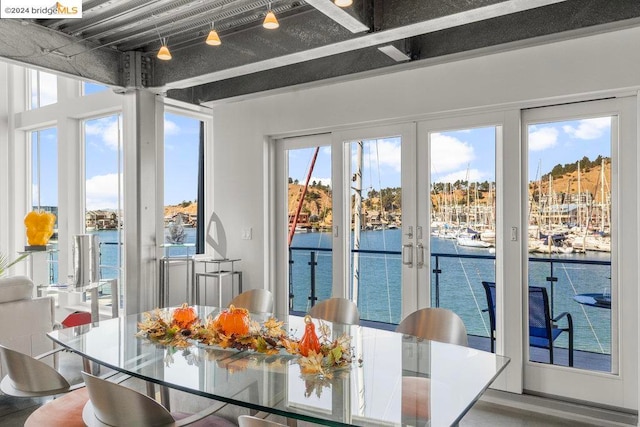 sunroom featuring a water view and french doors