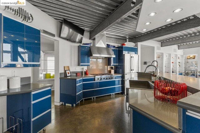 kitchen with beam ceiling, wall chimney range hood, stainless steel appliances, and blue cabinetry