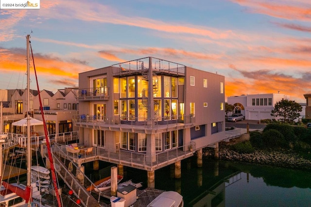 back house at dusk with a balcony and a water view