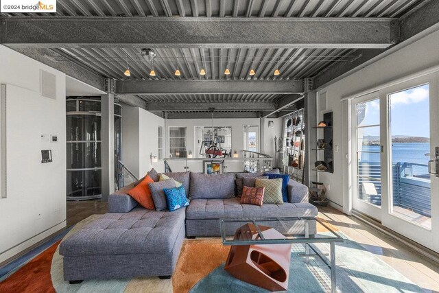 living room featuring wood-type flooring, beam ceiling, and a water view