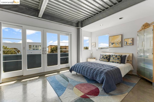 bedroom featuring french doors, multiple windows, access to outside, and concrete floors