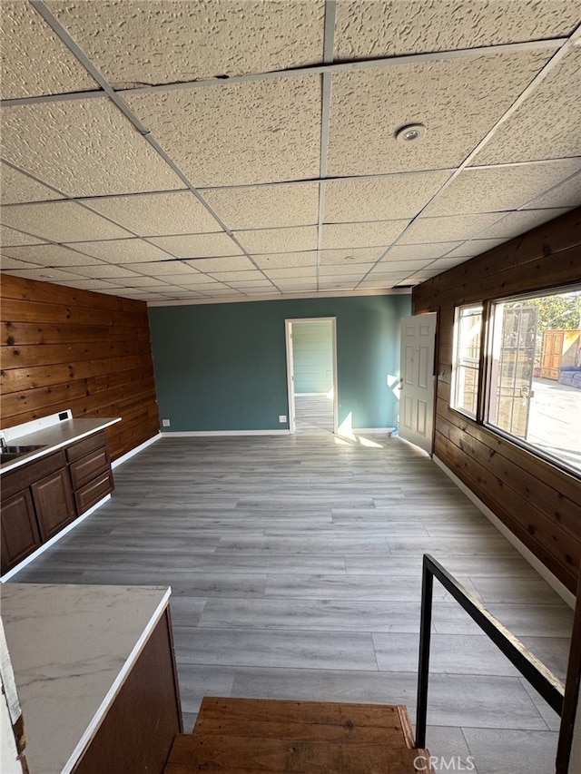 empty room featuring a paneled ceiling, wood-type flooring, and wooden walls