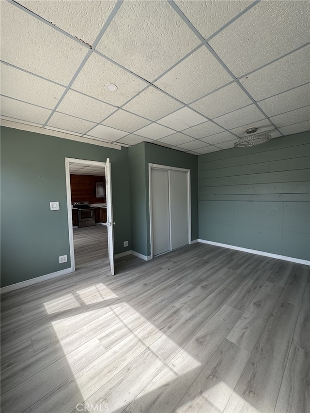 unfurnished bedroom featuring a closet, light hardwood / wood-style floors, and a drop ceiling