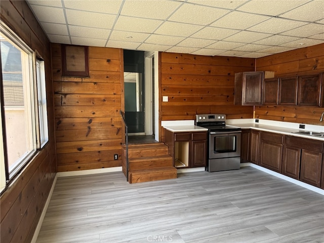 kitchen featuring a paneled ceiling, stainless steel electric range oven, and wood walls