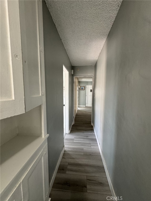 hallway with a textured ceiling and light wood-type flooring