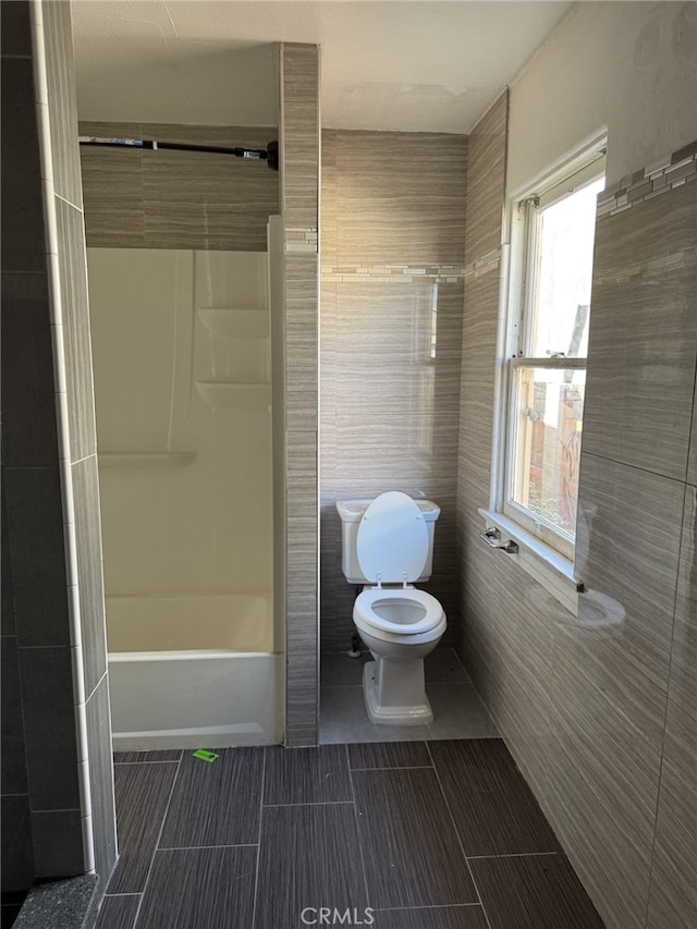 bathroom with toilet and tile walls