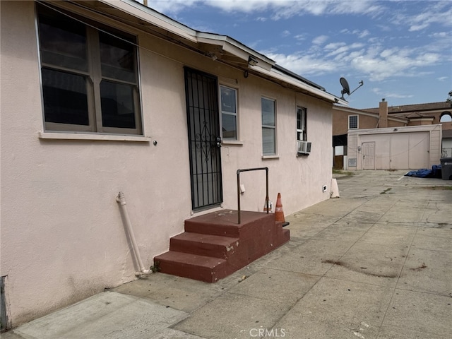 view of exterior entry featuring cooling unit and a patio