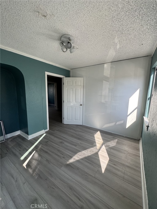 spare room featuring wood-type flooring, ornamental molding, and a textured ceiling