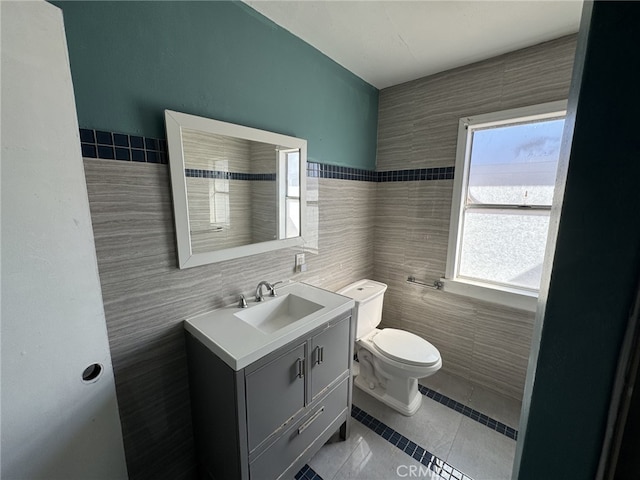 bathroom with toilet, tile patterned flooring, tile walls, and vanity