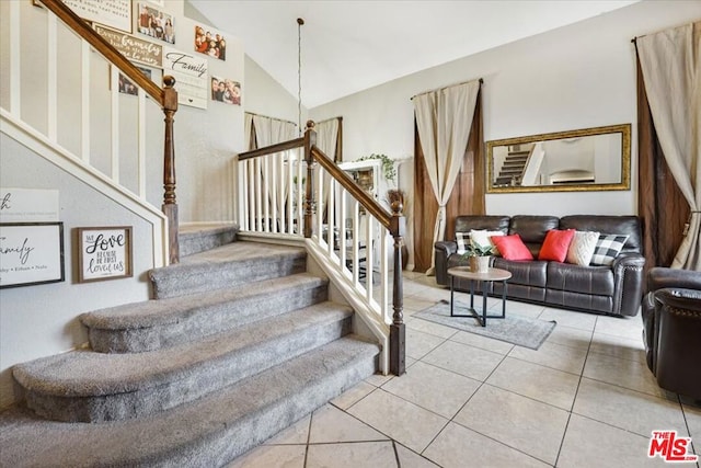 stairway with vaulted ceiling and tile patterned floors