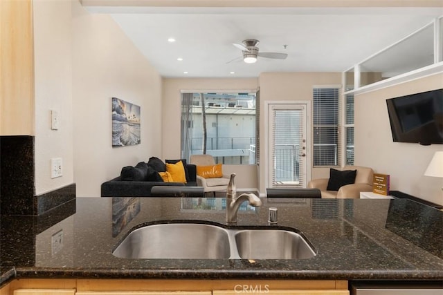 kitchen featuring ceiling fan, a healthy amount of sunlight, dark stone countertops, and sink