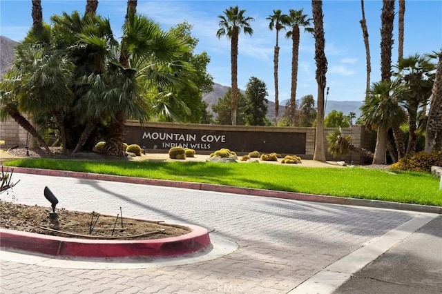 community / neighborhood sign featuring a mountain view and a lawn