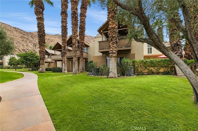 view of front of property featuring a balcony, a mountain view, and a front lawn