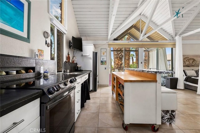 kitchen with sink, stainless steel fridge, white cabinets, light tile patterned flooring, and black / electric stove