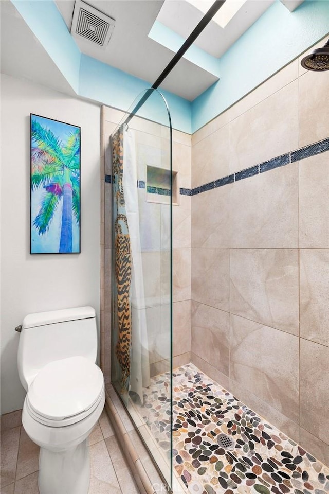 bathroom with tile patterned flooring, a shower with curtain, a skylight, and toilet