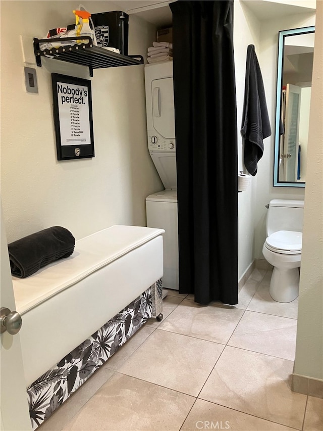 laundry area featuring light tile patterned flooring and stacked washer and dryer