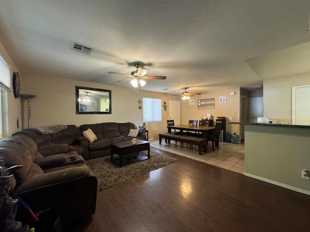 living room featuring ceiling fan, a textured ceiling, and light wood-type flooring