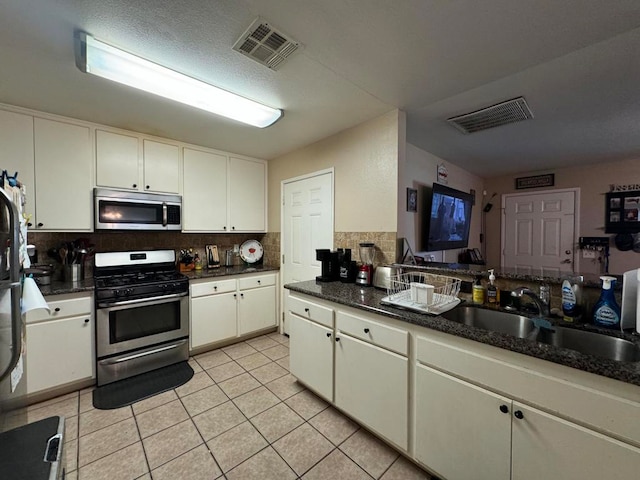 kitchen featuring stainless steel appliances, white cabinetry, tasteful backsplash, and sink