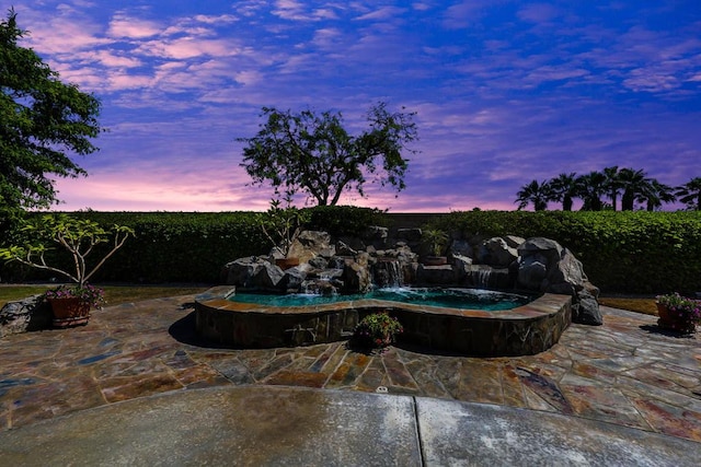 pool at dusk featuring a patio