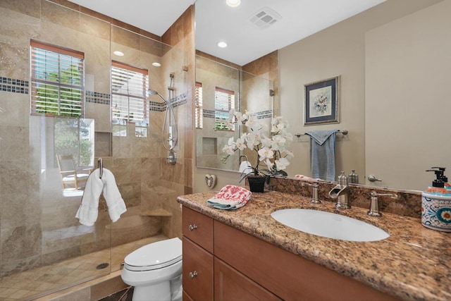 bathroom featuring vanity, toilet, and a shower with door