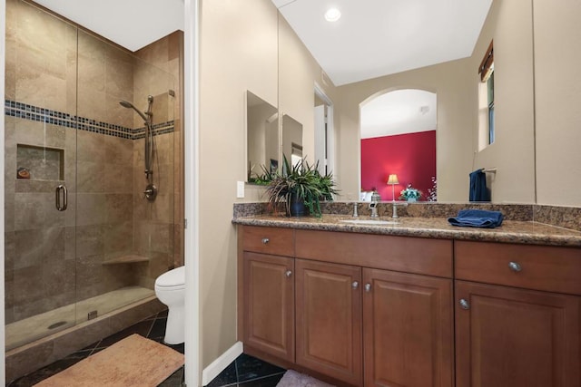 bathroom featuring tile patterned flooring, vanity, toilet, and walk in shower