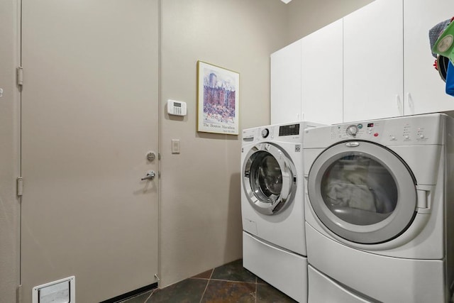 laundry room with cabinets, dark tile patterned flooring, and washer and clothes dryer