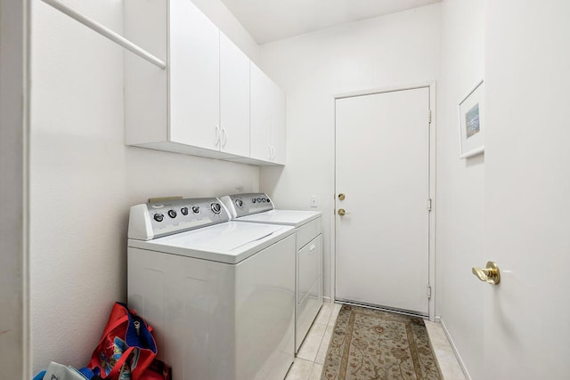 laundry room with cabinets, light tile patterned floors, and washing machine and dryer