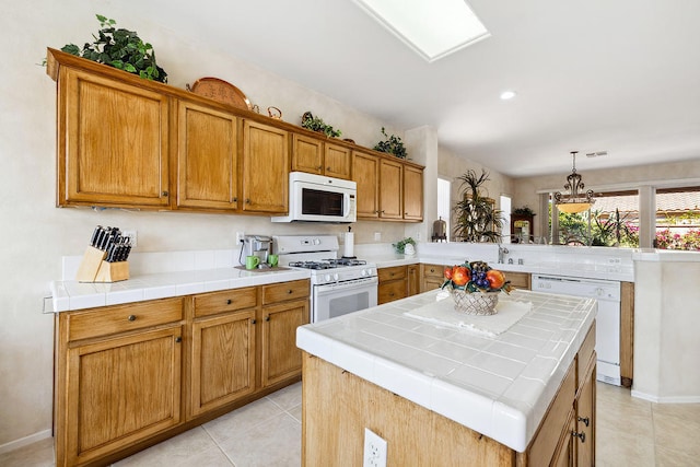 kitchen featuring tile counters, a center island, decorative light fixtures, white appliances, and light tile patterned flooring