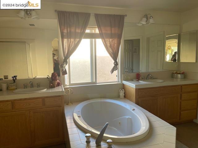 bathroom with a relaxing tiled tub and vanity