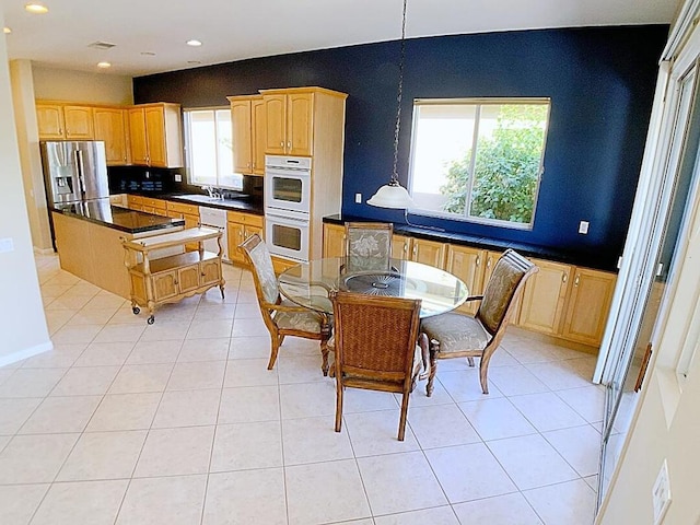 kitchen featuring white appliances, light tile patterned flooring, a kitchen island, and sink