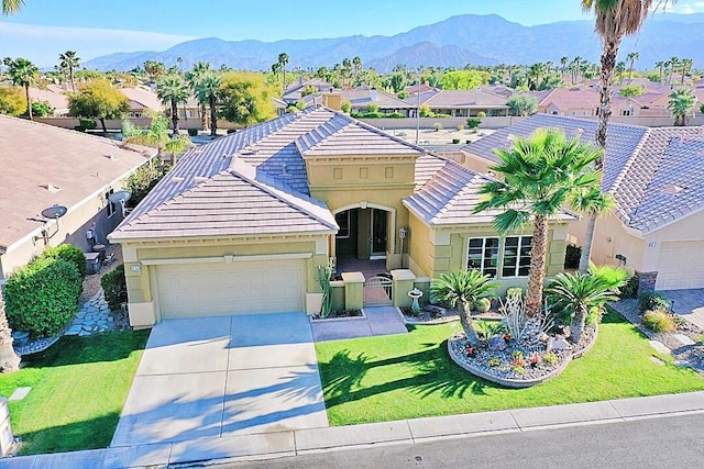 view of front of home featuring a mountain view, a garage, and a front lawn