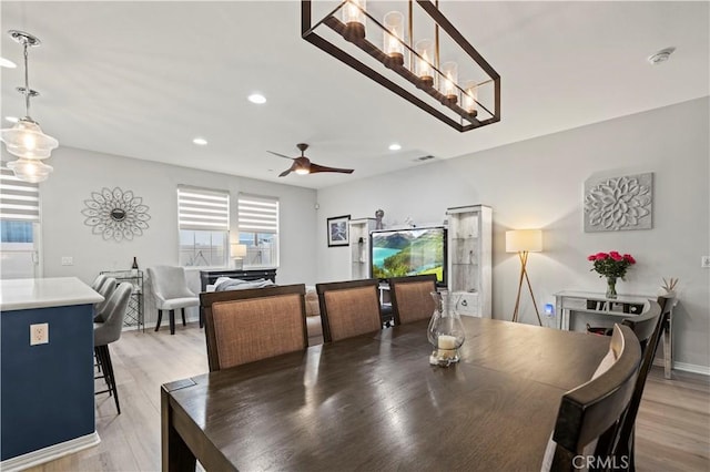 dining room featuring ceiling fan with notable chandelier and hardwood / wood-style flooring