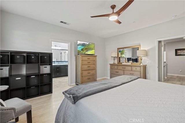 bedroom with connected bathroom, light hardwood / wood-style floors, and ceiling fan