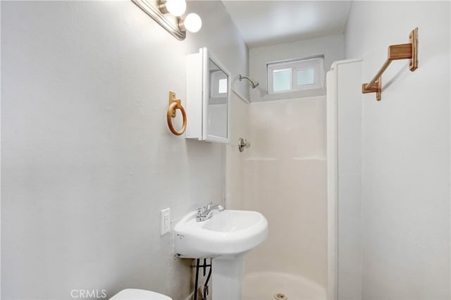 bathroom with walk in shower, toilet, and sink