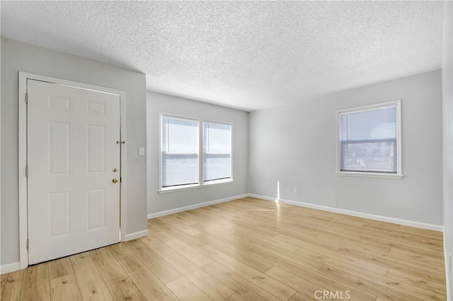 empty room with light hardwood / wood-style floors and a textured ceiling