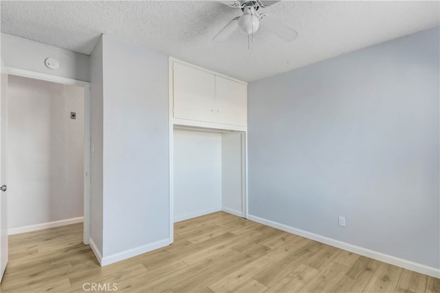 unfurnished bedroom with light wood-type flooring, a textured ceiling, ceiling fan, and a closet