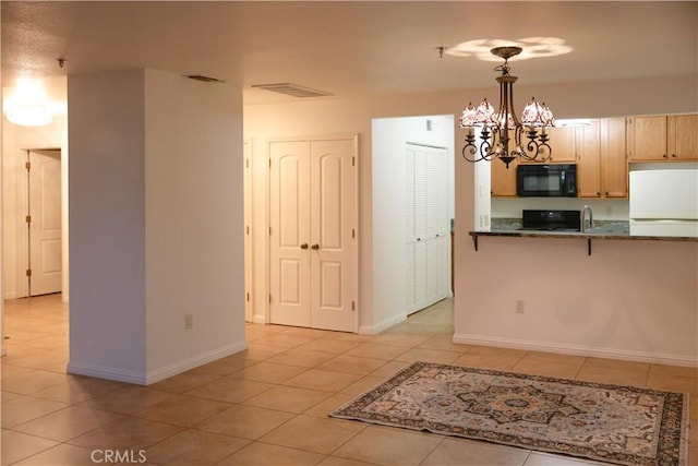 kitchen with light brown cabinetry, decorative light fixtures, a chandelier, refrigerator, and range with electric stovetop