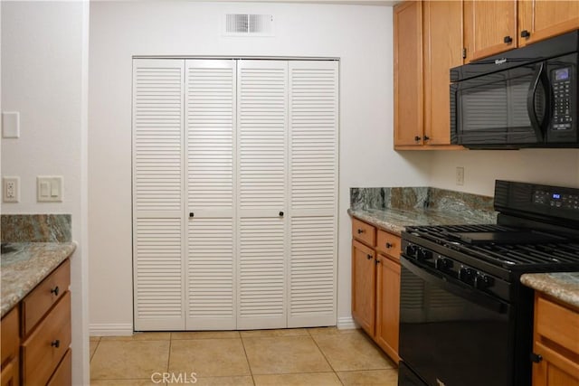 kitchen with light stone countertops, black appliances, and light tile patterned flooring