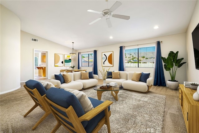 carpeted living room with ceiling fan with notable chandelier and vaulted ceiling