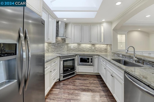 kitchen featuring white cabinets, appliances with stainless steel finishes, sink, and wall chimney range hood