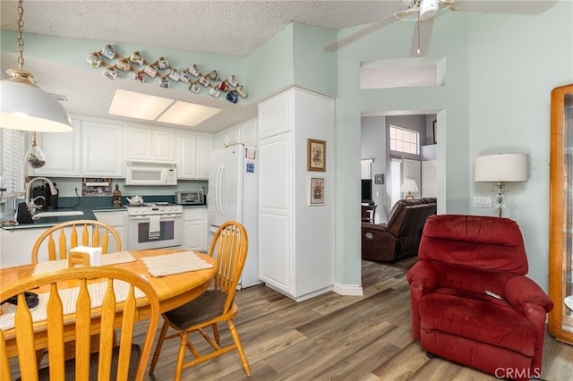 kitchen featuring a textured ceiling, white appliances, white cabinetry, and light hardwood / wood-style flooring