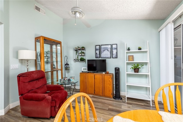 living room featuring wood-type flooring, vaulted ceiling, ceiling fan, and a textured ceiling