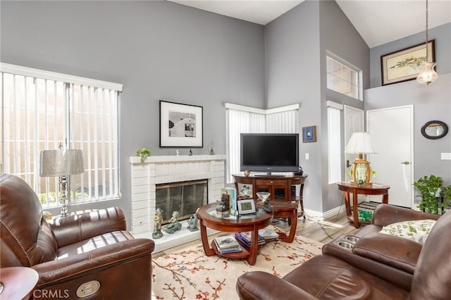 living room with high vaulted ceiling, a brick fireplace, and hardwood / wood-style flooring