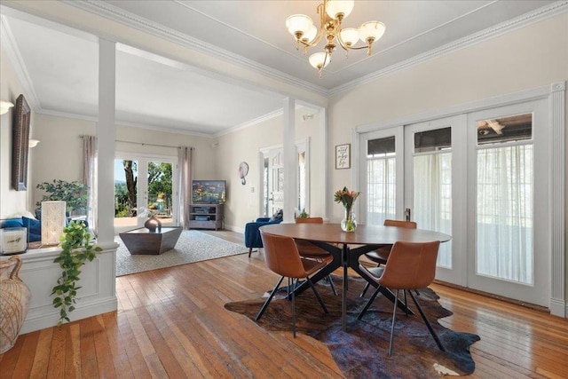 dining area with french doors, crown molding, an inviting chandelier, and hardwood / wood-style floors