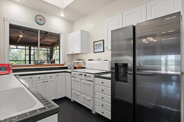 kitchen featuring white cabinetry, electric stove, sink, and stainless steel fridge