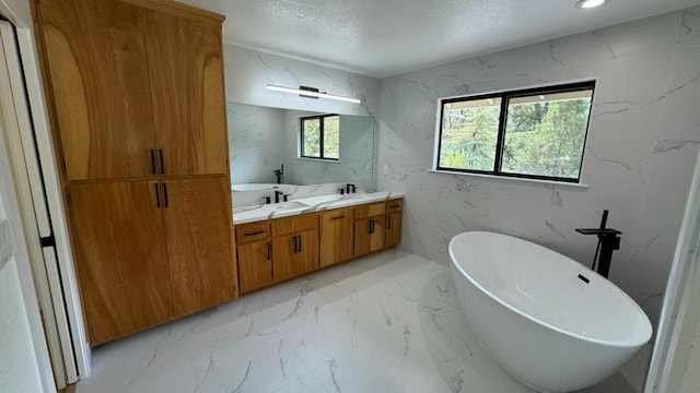 bathroom with vanity, a wealth of natural light, a textured ceiling, and a tub