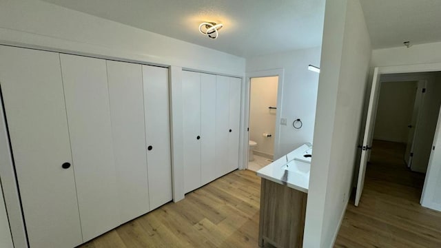 interior space featuring light hardwood / wood-style floors, sink, connected bathroom, and two closets